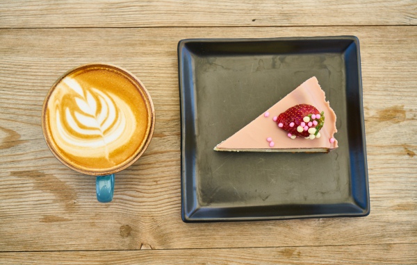 Кусок торта на черной тарелке с кофе