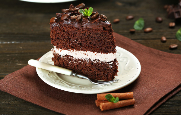 Кусок шоколадного торта с кремом и зернами кофе