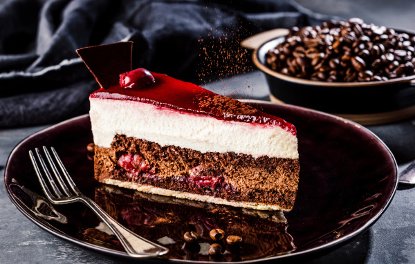 Аппетитный торт с суфле и вишнями на столе с кофейными зернами