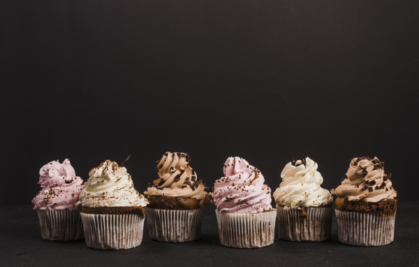 Аппетитные кексы с кремом на сером фоне