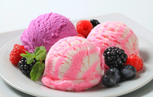 Шарики фруктового мороженого на белой тарелке с ягодами