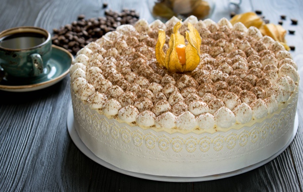 Красивый праздничный торт с цветком физалиса на столе с кофе