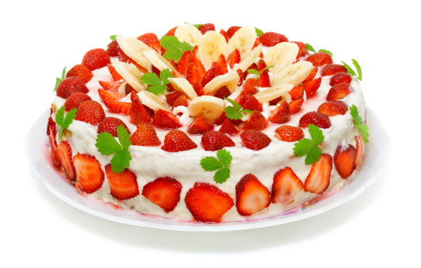 Большой торт с клубникой и бананами на белом фоне