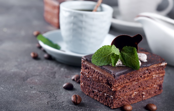 Шоколадное пирожное на столе с чашкой кофе