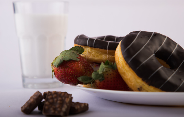 Пончики с шоколадной глазурью на тарелке с клубникой