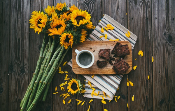 Cup of coffee on the table with a pie and a bouquet of sunflowers