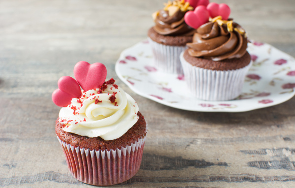 Кекс с кремом и красными сердечками на столе 