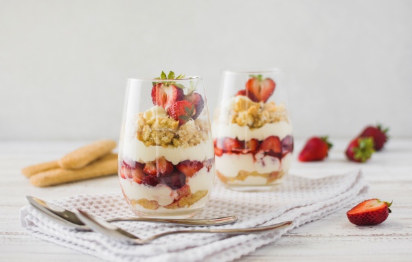Десерт с клубникой в стеклянных стаканах на столе 