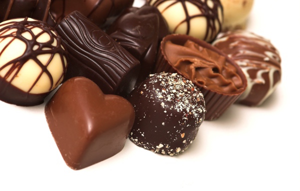 Разные шоколадные конфеты на белом фоне 