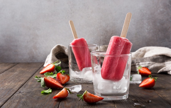 Фруктовое мороженое в стакане со льдом на столе с клубникой