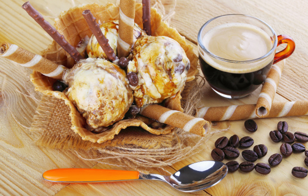 Мороженое с трубочками на столе с кофейными зернами и кофе