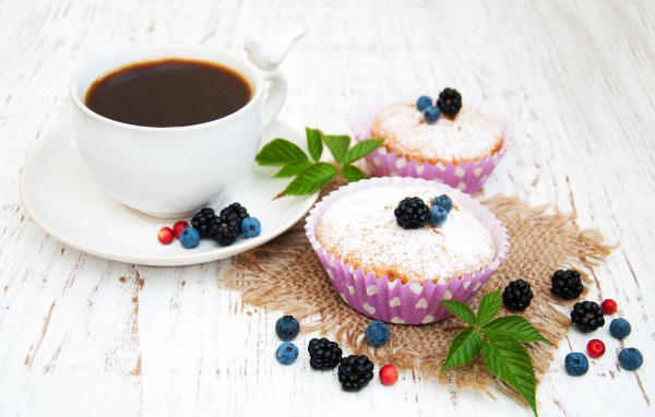 Кексы с сахарной пудрой и ягодами на столе с какао