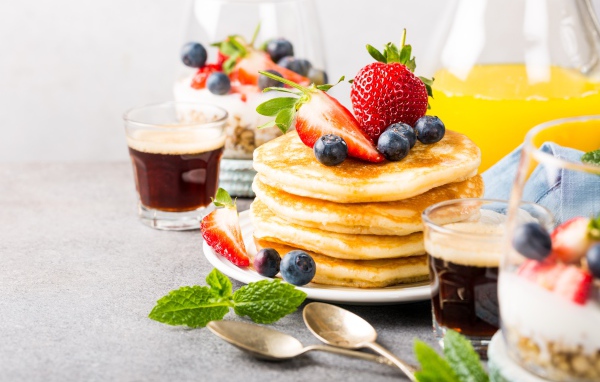 Оладьи с ягодами на столе с соком