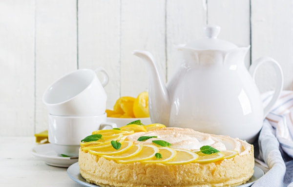 Вкусный песочный пирог с лимоном на столе с чашками и чайником