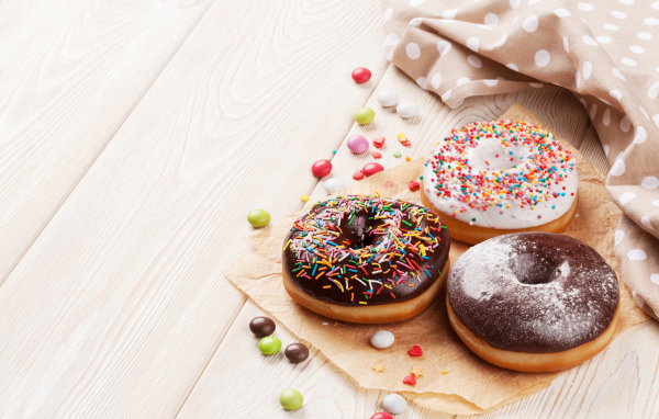 Три аппетитных пончика с глазурью на столе 