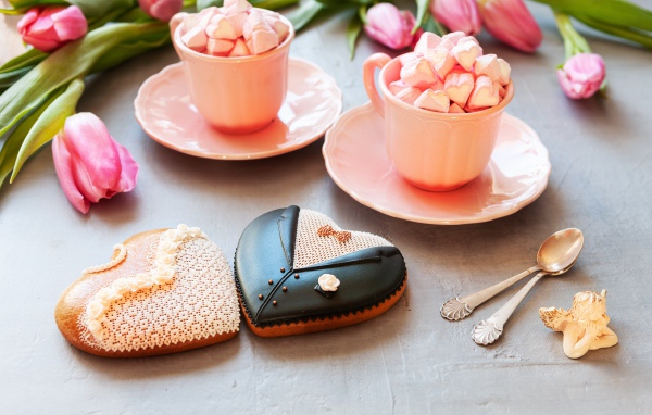 Две розовые чашки с маршмеллоу на сером фоне с печеньем и тюльпанами