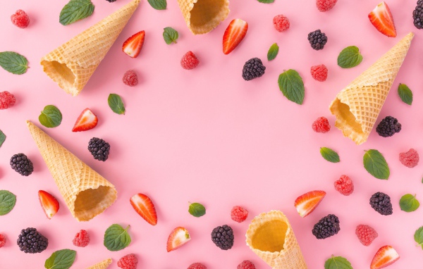 Вафельные рожки на розовом фоне с ягодами малины, клубники и ежевики