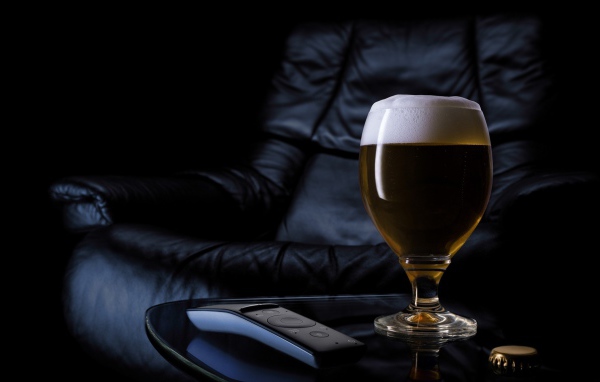Бокал пива на фоне черного кожаного кресла