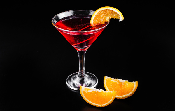 Алкогольный коктейль с кусочками апельсина на черном фоне