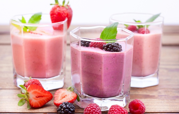 Ягодное смузи в стаканах на столе с ягодами малины, черники и клубники