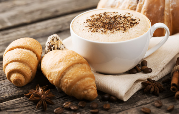 Чашка капучино на столе круассанами