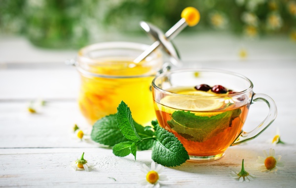 Чашка чая с лимоном и мятой на столе с медом