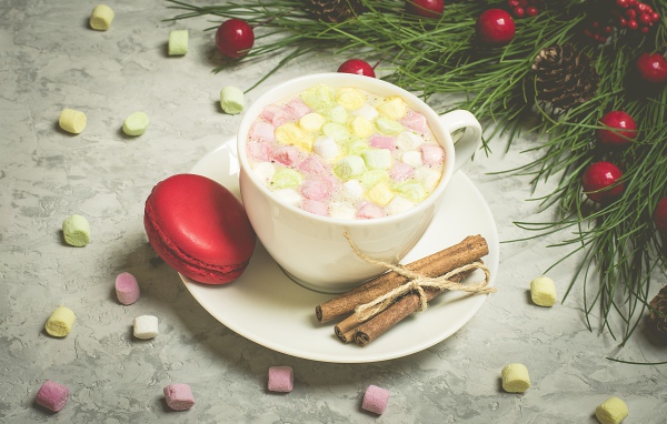 Напиток с маршмелоу на блюдце с макаруном и корицей