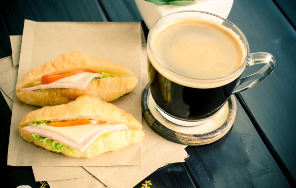 Стеклянная чашка кофе на столе с сэндвичами