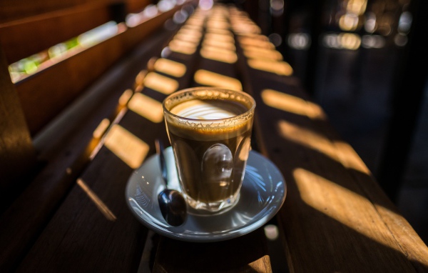 Стакан с кофе стоит на деревянном лавке