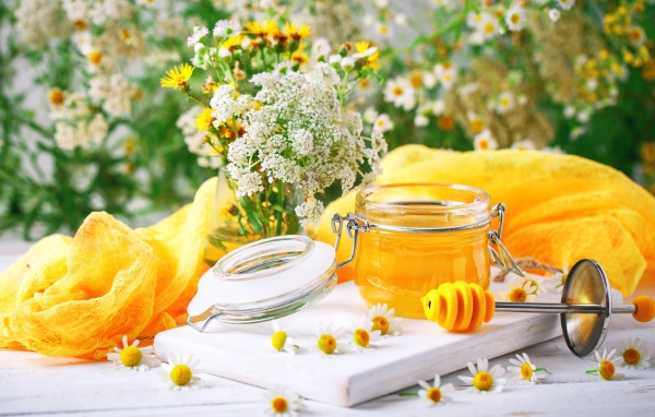 Банка меда на столе с цветами
