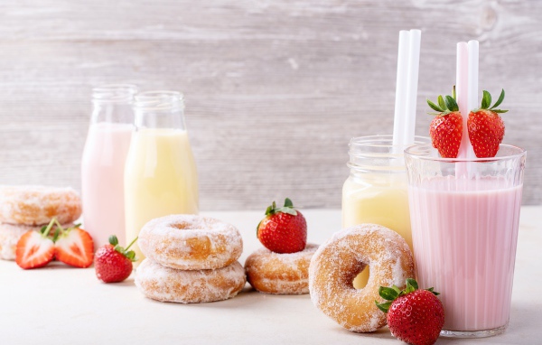Молочные коктейли на столе с клубникой и пончиками