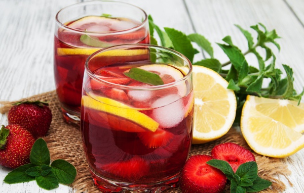 Мохито в стаканах на столе с клубникой, лимоном и мятой