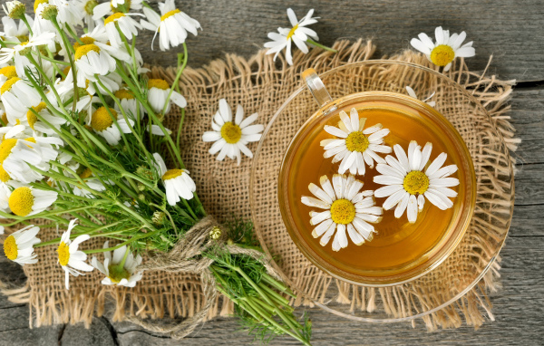 Чай в стеклянной чашке на столе с ромашкой