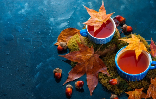 Чай на столе с осенними листьями и желудями 