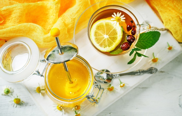 Чай с лимоном и шиповником на столе с медом