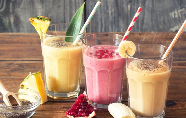 Три стакана смузи на столе с трубочками