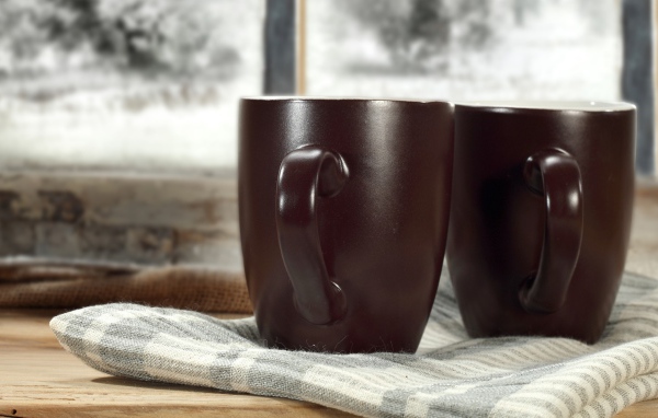 Две коричневые чашки кофе на столе с шарфом
