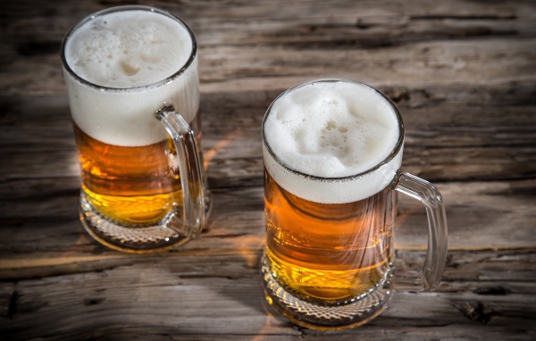 Два бокала пива с пеной на деревянном столе