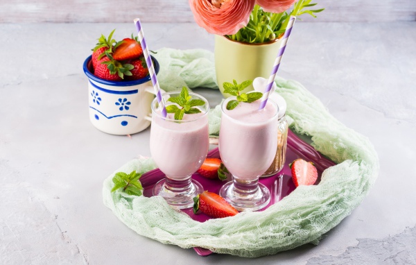 Два стакана с коктейлем на столе с букетом и клубникой