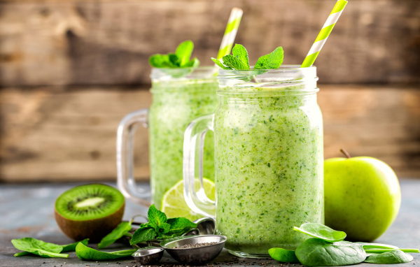 Два зеленых смузи на столе с киви, мятой и зеленым яблоком