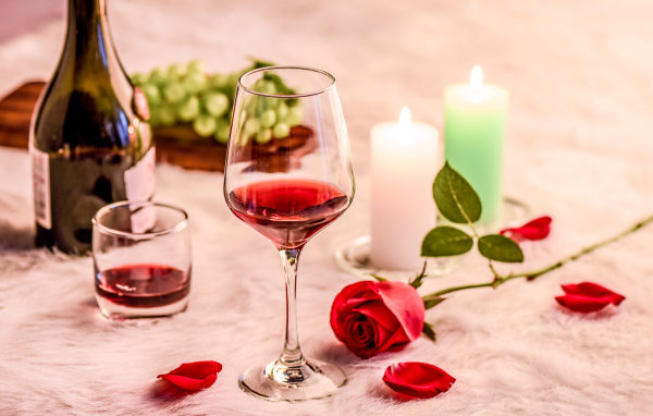 Вино на кровати с розой, виноградом и зажженными свечами