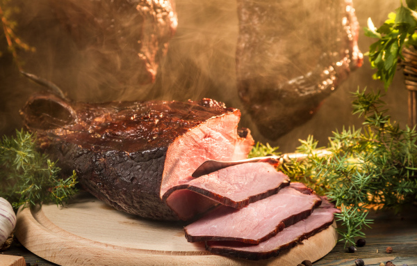 Аппетитный кусок сочной ветчины нарезан на разделочной доске