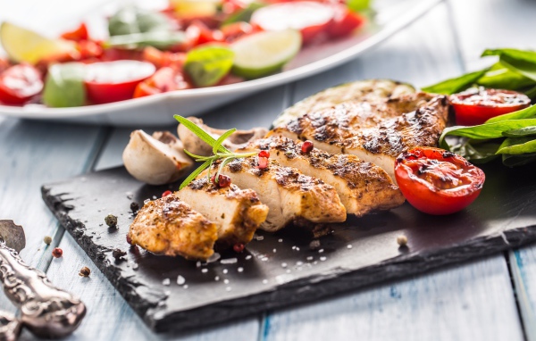 Запеченное куриное мясо на доске с помидорами 