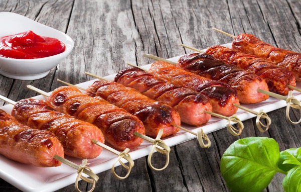 Сосиски гриль на шпажках на столе с соусом