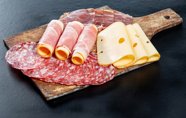 Ветчина на доске с колбасой и твердым сыром