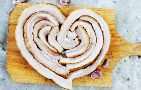 Сердце из свежего сала на доске с чесноком