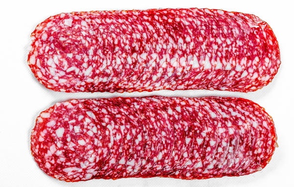 Колбаса салями нарезанная тонкими кусочками на белом фоне