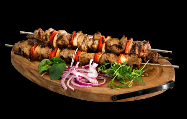 Шашлык на разделочной доске с луком и зеленью 