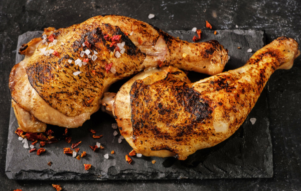 Два запеченных куриных окорочка на черном фоне