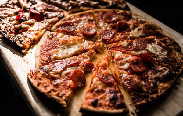 Пицца нарезана кусками на деревянной доске